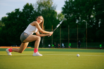 girl hockey player plays field hockey on a sunny day, the hockey player hits the ball with a stick