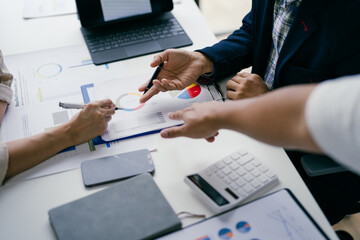 Business Team Analyzing Financial Data and Graphs in a Modern Office Setting with Digital Devices and Documents