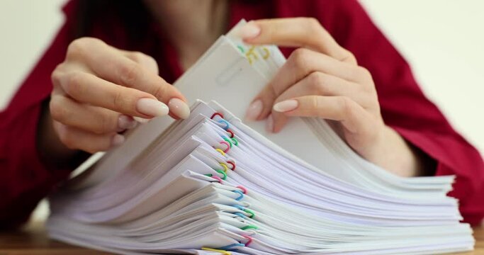 Secretary checks papers attached with clips pile in office