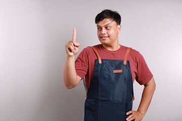 Man wearing a blue apron showing and lifting a finger in sign of the best on white background