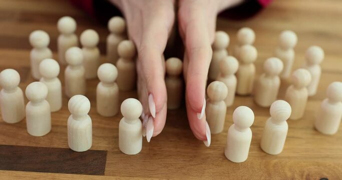 Hands split up lone wooden figure from pawns on table