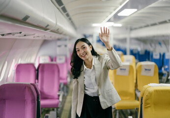 Businesswoman Waving Inside Airplane Cabin with Colorful Seats, Smiling and Greeting Passengers