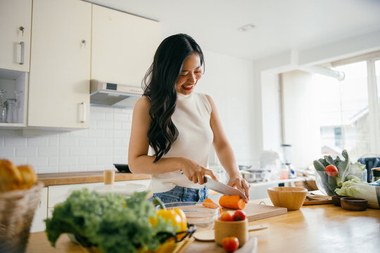Young Woman Preparing Fresh Vegetables in a Bright Modern Kitchen with Natural Light - Powered by Adobe