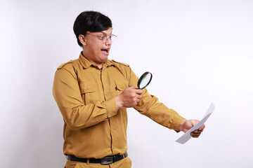 Happy Indonesian government employees standing while reading a report through a magnifying glass