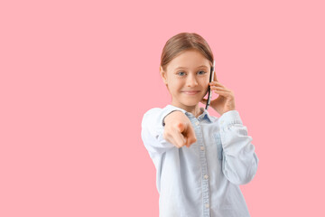 Little girl talking by mobile phone on pink background