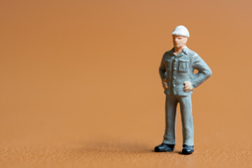 Miniature construction worker. A man dressed in a blue work uniform, complete with a hard hat. He stands confidently with his hands on his hips