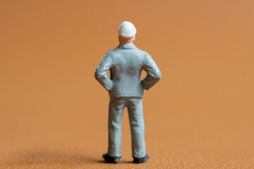 Miniature construction worker. A man dressed in a blue work uniform, complete with a hard hat. He stands confidently with his hands on his hips