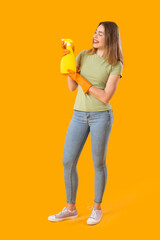 Young woman with bottle of detergent on orange background