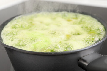Saucepan with boiling gooseberry jam on electric stove