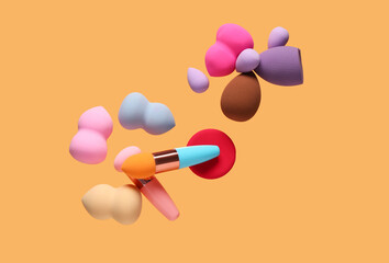 Flying different makeup sponges on orange background