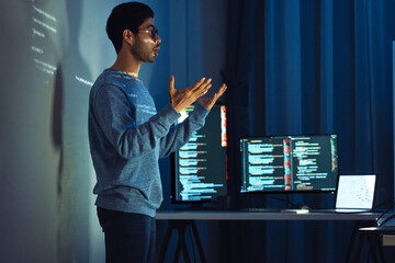 Indian man programmer standing in front of a screen with code projected  presentation the...