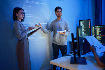 asian developer leads present code review session, pointing at code projected on the wall with...
