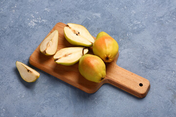 Wooden board with fresh pears on blue background