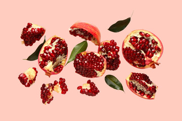 Flying fresh pomegranates and leaves on pink background