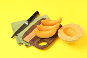 Wooden board with pieces of sweet melon on yellow background