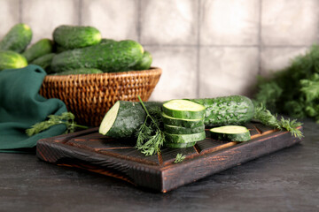 Wooden board with fresh cucumbers on table