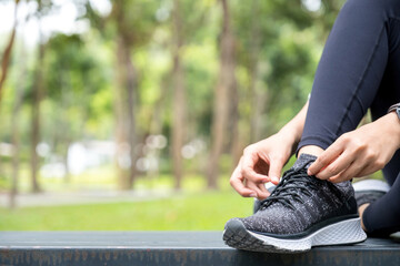 Woman tying shoe laces at park.