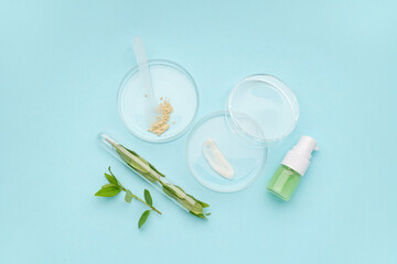 Petri dishes with samples, plant leaves and bottle of cosmetic product on blue background