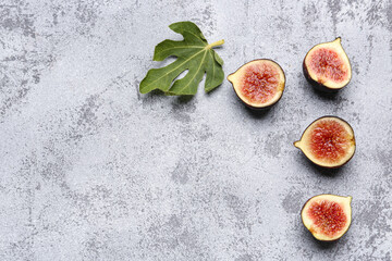 Halves of fresh ripe figs and leaf on blue background