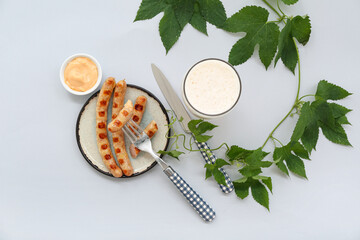 Plate with tasty Bavarian sausages, sauce and glass of beer on grey background. Oktoberfest celebration