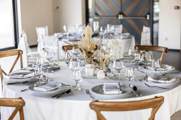 A wedding table covered with a white tablecloth, decorated with flowers, candles, glasses and cutlery.