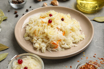Plate with delicious sauerkraut and different spices on grey background