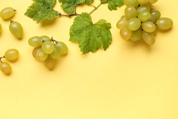 Fresh green grapes with leaves on yellow background