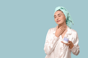 Young woman with jar of cream on blue background