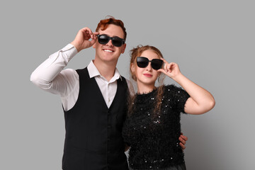 Young couple in sunglasses on grey background. Black Friday sale