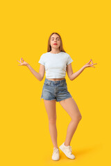 Beautiful young woman meditating on yellow background. Zen concept
