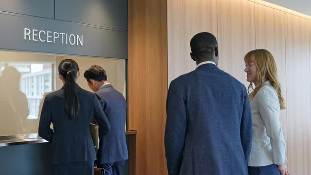 A group of multinational business people processing documents at a reception desk