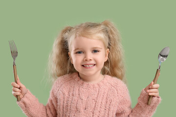 Cute little girl with fork and knife on green background