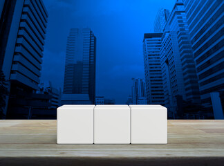 Three white block cubes on wooden table over modern office city tower and skyscraper
