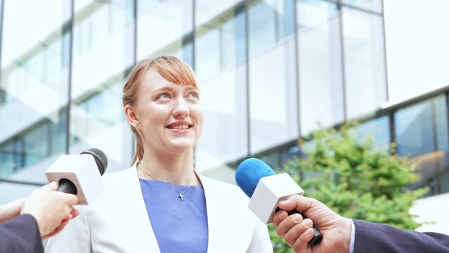 A Caucasian woman being interviewed in front of a building