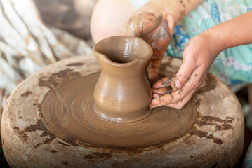 Human hand sculpting a craft from raw clay