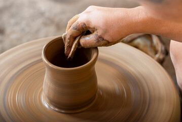 Human hand sculpting a craft from raw clay