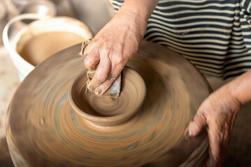 Human hand sculpting a craft from raw clay