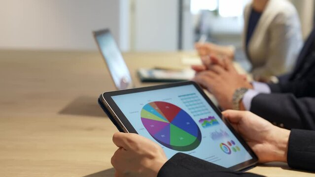 タブレット画面を見ながら会議するビジネスパーソン