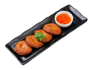 Thai style fried fish cakes with sweet dipping sauce on black plate isolated on white background.
