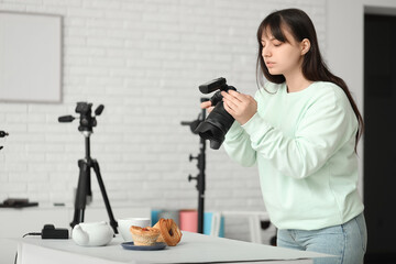 Fototapeta premium Female food photographer taking picture of cakes in studio