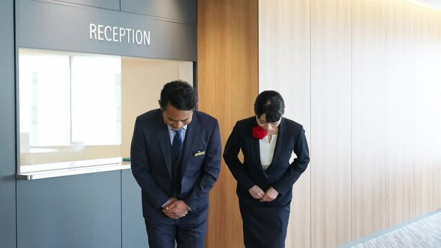 お辞儀するホテルフロントスタッフ