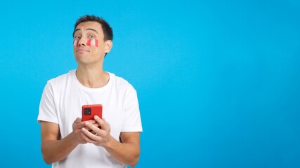 Peruvian supporter looking at his mobile smiling and showing it.
