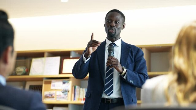 Black businessman giving a speech in front of an audience