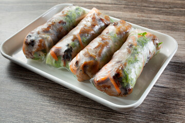 A view of a plate of spring rolls, featuring grilled pork.