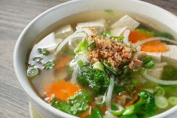 A closeup view of a veggie pho bowl with chicken broth.