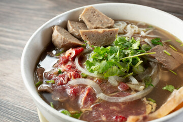 A view of a bowl of pho, featuring rare steak, flank, tendon, and tripe.