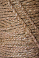 Natural brown rope, rough texture and intertwined fibers. The detailed view highlights the rope's robust and rustic quality, making it ideal for various craft and design projects.