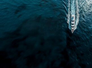 Aerial view of a lavish yacht cruising on serene ocean waters, leaving a frothy trail