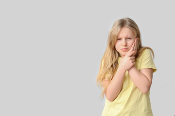 Young girl suffering from toothache on grey background