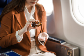 A young Asian woman is sitting in her seat as an airplane passenger, experiencing airsickness with symptoms like nausea, vomiting, dizziness, and general discomfort.